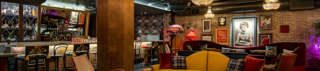 Cozy lounge with chandeliers, colorful seating, a bar area, and warm decor creating an intimate, stylish vibe throughout the space.