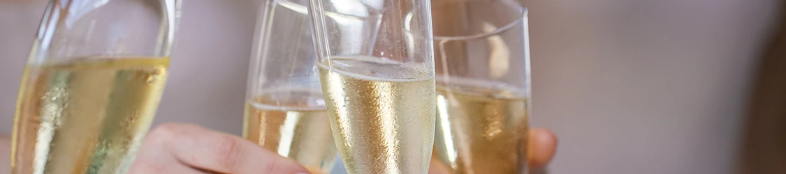 People toasting with flutes of champagne in a celebration, clinking glasses.