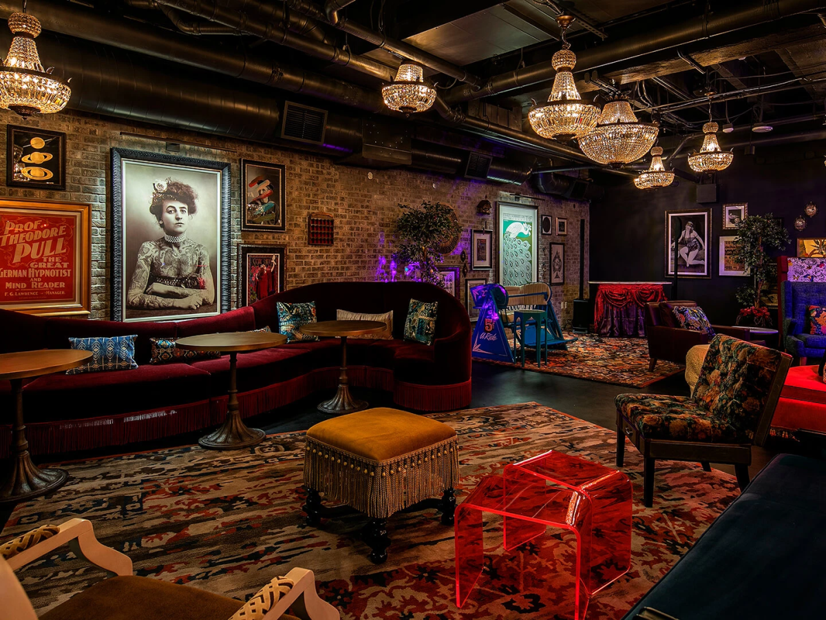 A stylish, retro lounge with vintage posters, chic seating, warm lighting, and eclectic decor in a cozy, art-filled room.